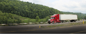 Red and white colored flat bed trucking company moving on the highway is shown in the image